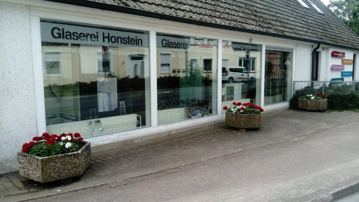 Ladengeschäft der Glaserei Honstein in der Sudweyher Straße, mit beschrifteter Schaufensterscheibe und Blumenkübeln davor